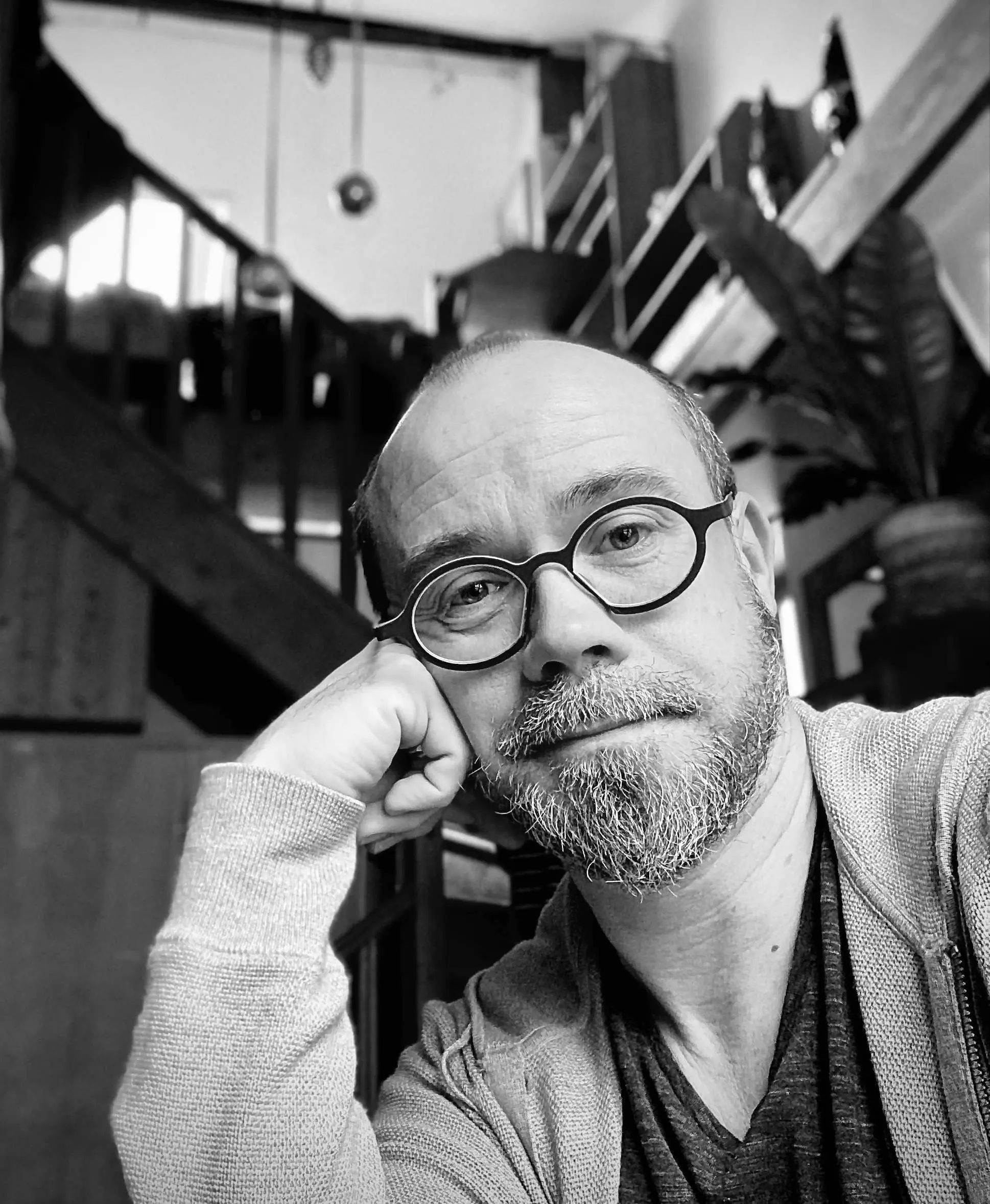 jean-benoit-dumonteix-psy-varzy Portrait en noir et blanc de Jean Benoit Dumonteix, psychologue clinicien à l'écoute, avec une barbe et des lunettes, assis sur un canapé, inspirant confiance et expertise.