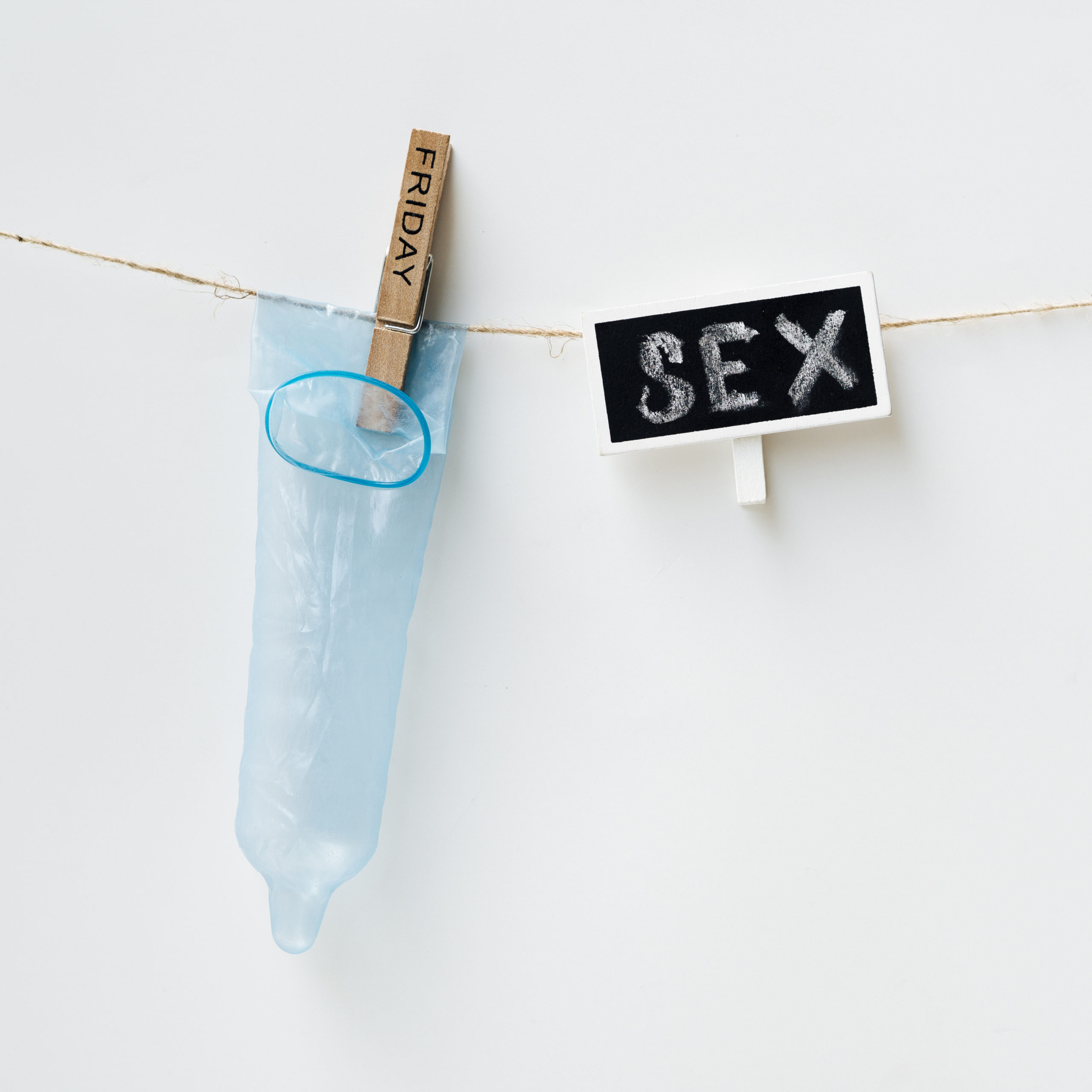 illustration d'un préservatif bleu sur un fond blanc et accroché sur un fil avec une affiche "sex"